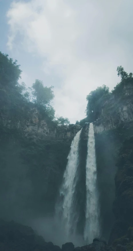 a large waterfall in the middle of a forest, style of ade santora, low quality photo, indonesia, jaime jasso