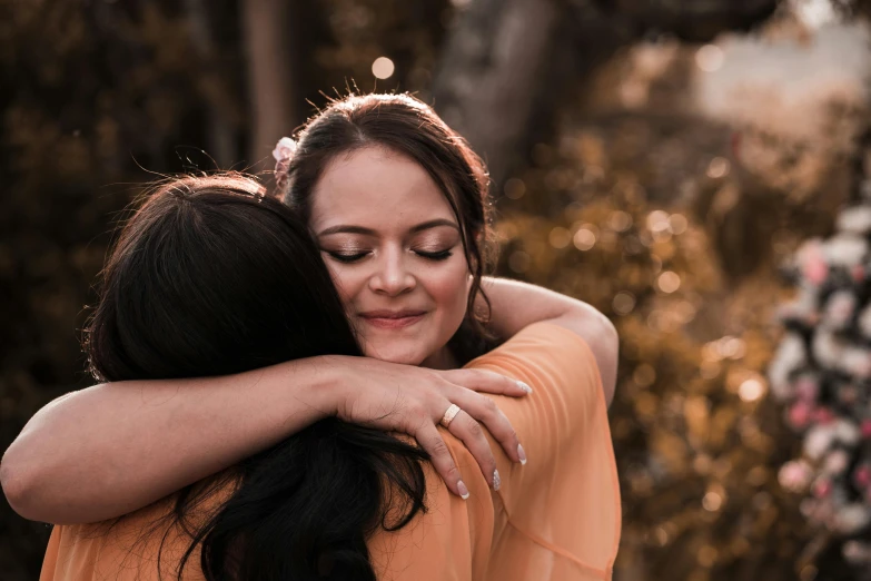 a couple of women standing next to each other, pexels contest winner, happening, sweet hugs, manuka, brunettes, warm coloured