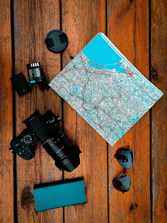 a map sitting on top of a wooden table next to a camera, teal cloth, high quality product image”, dwell, neoprene