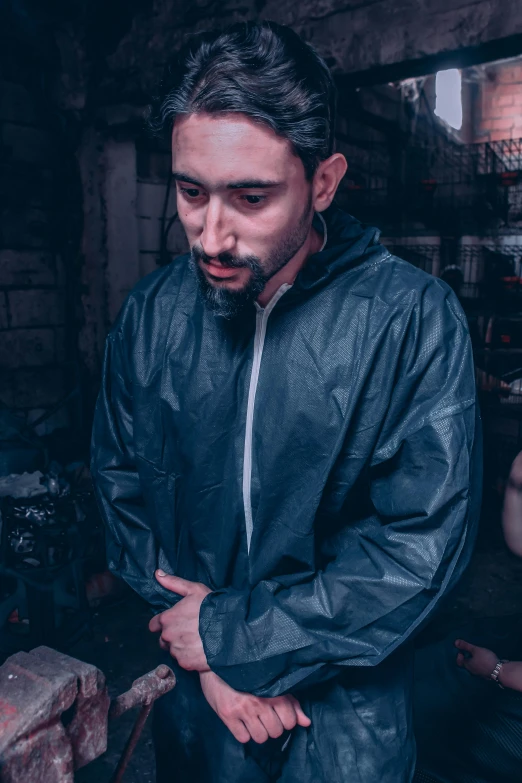 a man in a raincoat standing in a workshop, an album cover, by Alejandro Obregón, featured on reddit, hyperrealism, techwear clothes, headshot profile picture, desaturated, tracksuit