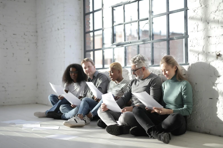 a group of people sitting next to each other on the floor, redundancy, reading, realistic »