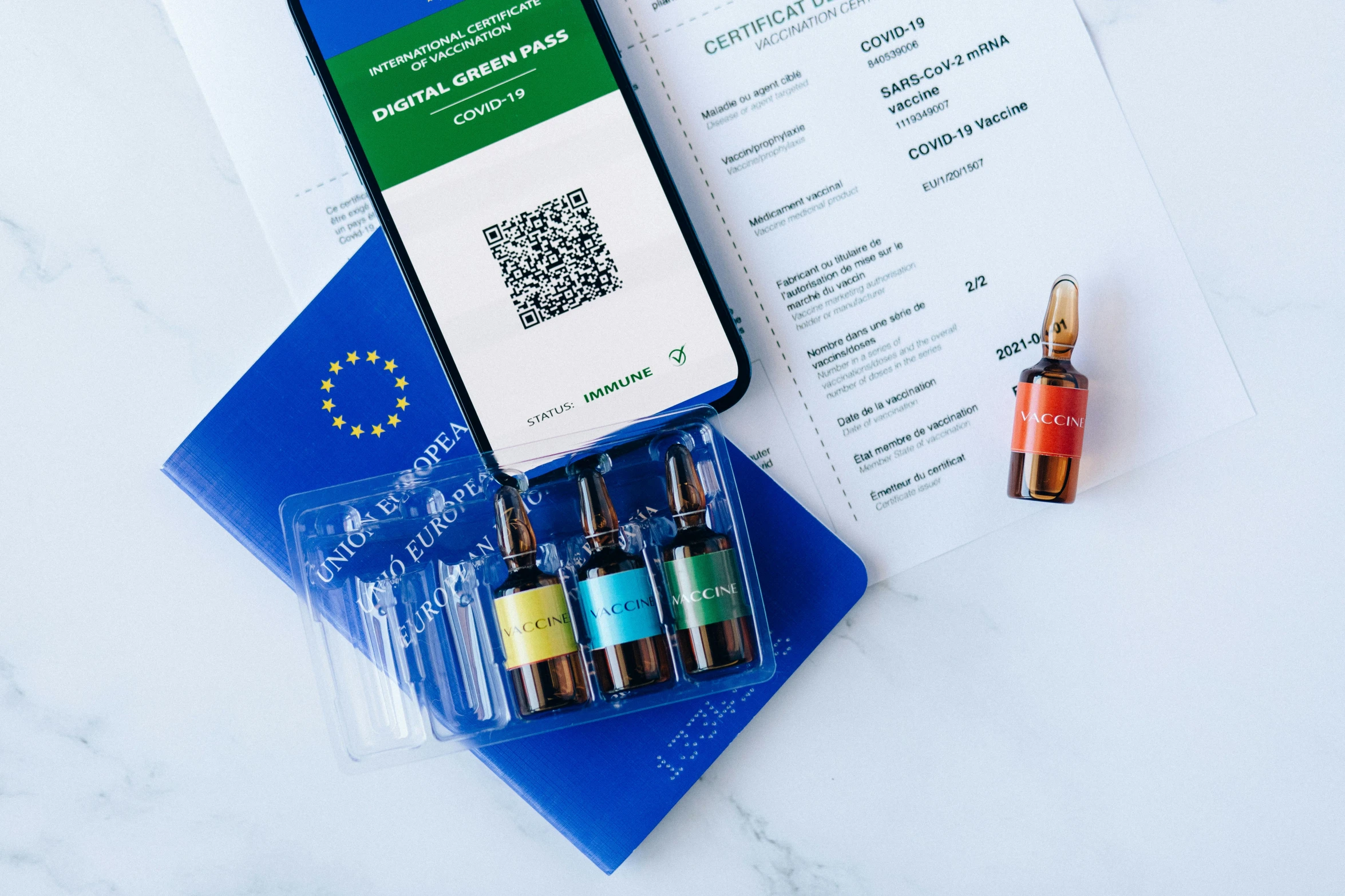 a cell phone sitting on top of a table next to a passport, a picture, vibrant vials, product label, green and blue, western european