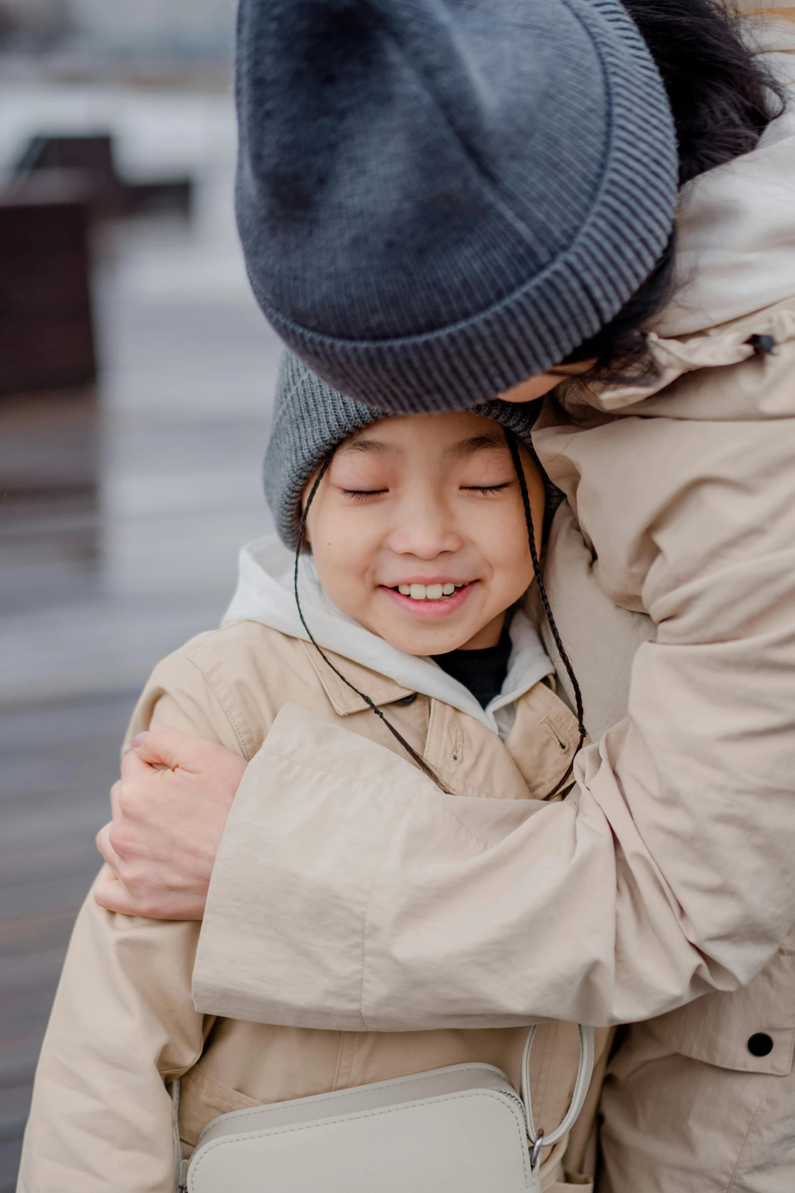 a close up of a person hugging a child, wearing jacket, square, asian human, grey