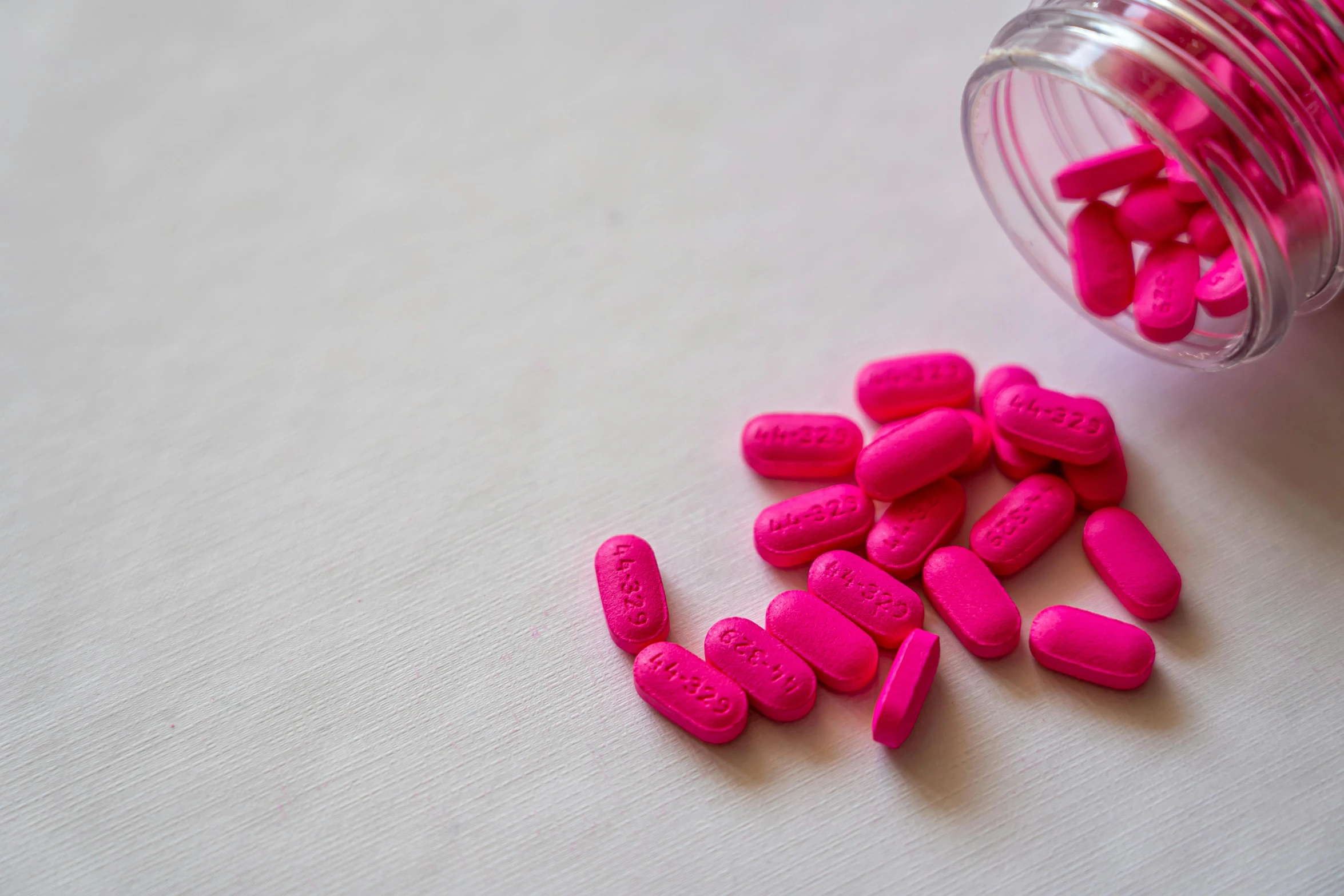 a jar filled with pink pills sitting on top of a table, pexels, antipodeans, fuchsia, ((pink)), cover shot, coloured