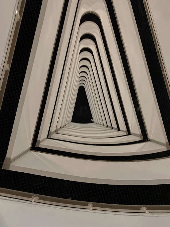 a black and white photo of the inside of a building, unsplash contest winner, abstract illusionism, cardboard tunnels, in triangular formation, looking down at you, in a row