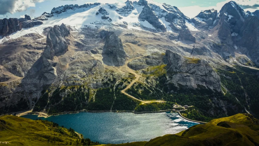 a large body of water sitting on top of a lush green hillside, a matte painting, by Carlo Martini, pexels contest winner, snowy peaks, top down view, conde nast traveler photo, lago di sorapis