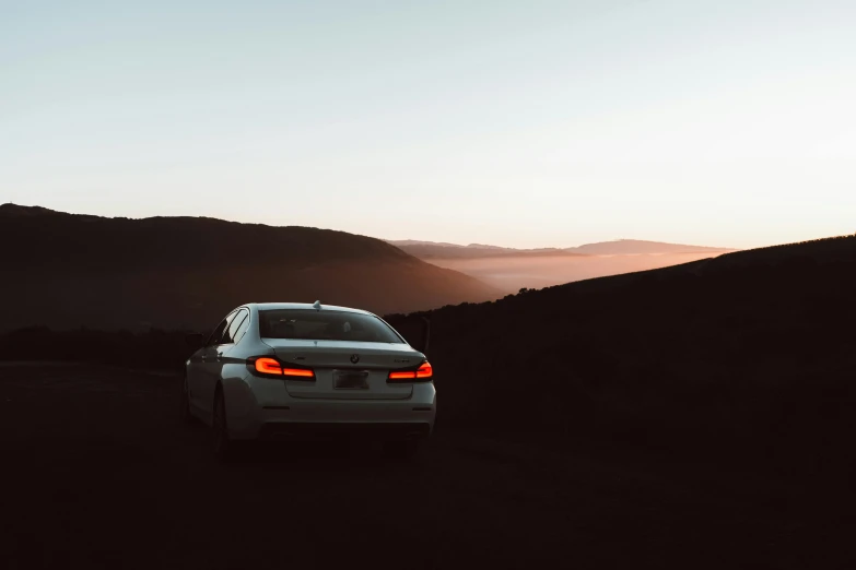 a car that is sitting on the side of a road, pexels contest winner, romanticism, back lit, hills, bmw, minimalist environment