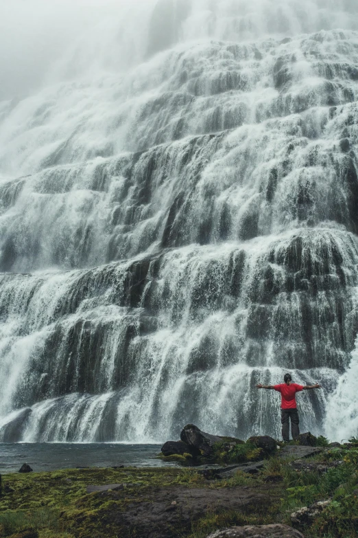 a person standing in front of a waterfall, by Jesper Knudsen, hurufiyya, a gigantic wall, full frame image