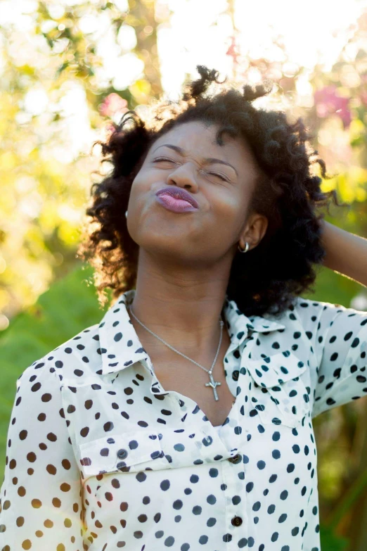a woman with her eyes closed wearing a polka dot shirt, by Dulah Marie Evans, trending on pexels, happening, tongue out, natural complexion, lush surroundings, graphic”