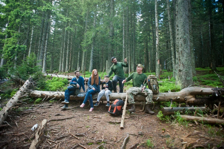 a group of people sitting on a log in the woods, pexels contest winner, hurufiyya, carpathian mountains, avatar image, family photo, camping