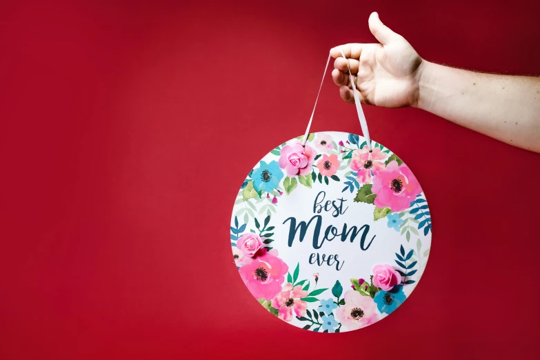 a person holding a sign that says best mom ever, an album cover, by Julia Pishtar, pexels contest winner, paper decoration, round format, flowery, panel