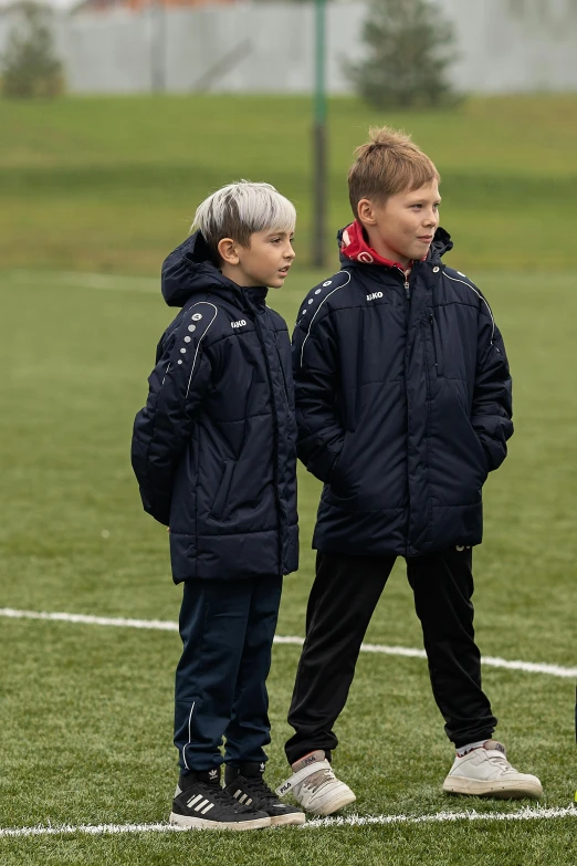 a group of young boys standing on top of a soccer field, pexels, model wears a puffer jacket, product introduction photo, medium shot of two characters, 15081959 21121991 01012000 4k