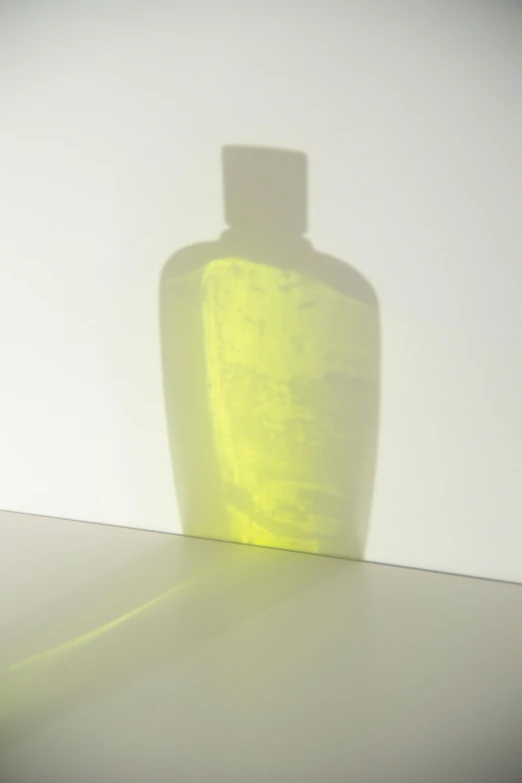 a yellow bottle sitting on top of a table, a picture, by Shigeru Aoki, cast shadows, translucent neon skin, reflective skin, difraction from back light