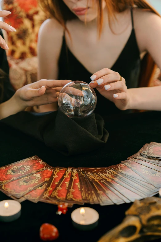 a woman holding a crystal ball sitting on top of a table