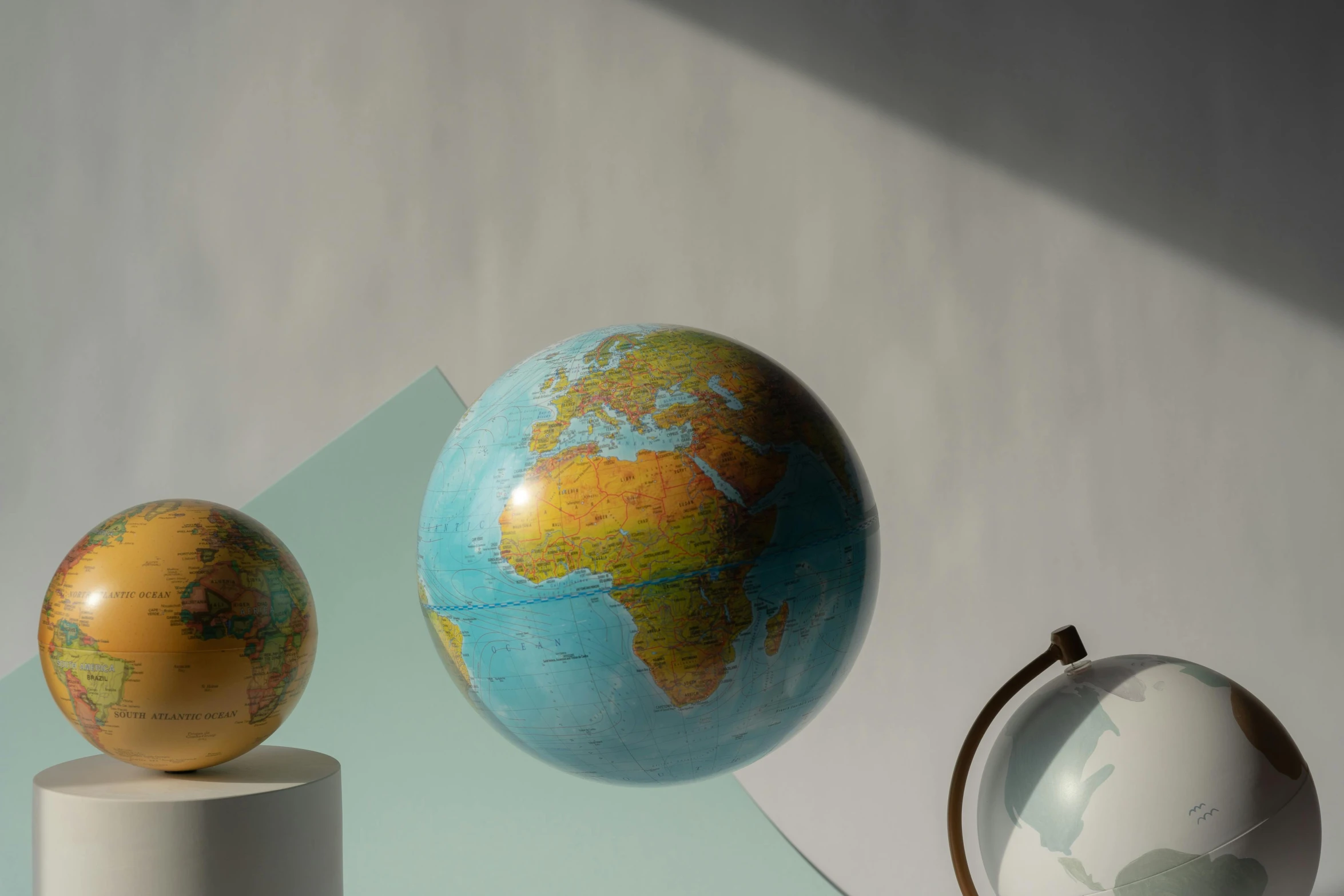 a couple of globes sitting on top of a table, a raytraced image, trending on unsplash, hyperrealism, earth and pastel colors, pbr materials, mercator projection, three fourths view