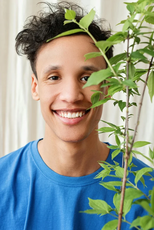 a close up of a person holding a plant, inspired by John Luke, smiling male, profile image, color photo, natural complexion