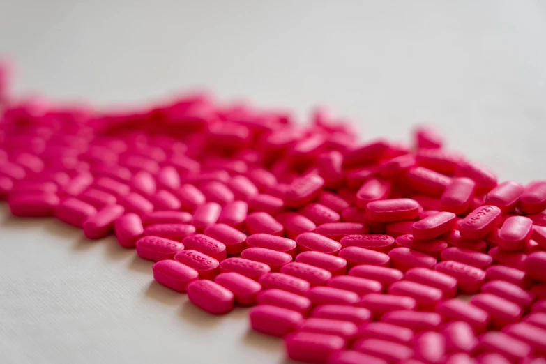 a pile of pink pills sitting on top of a table, by Sebastian Vrancx, antipodeans, magenta colours, sharply detailed, a close-up, ap photo