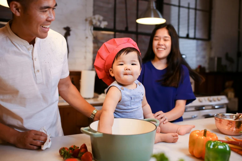 a man and woman in a kitchen with a baby, pexels contest winner, chef hat, asian features, thumbnail, brown