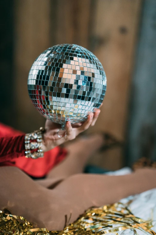 a woman in a red dress holding a disco ball, an album cover, by Julia Pishtar, trending on pexels, in a silver silk robe, dance party, medium close up, disco ball