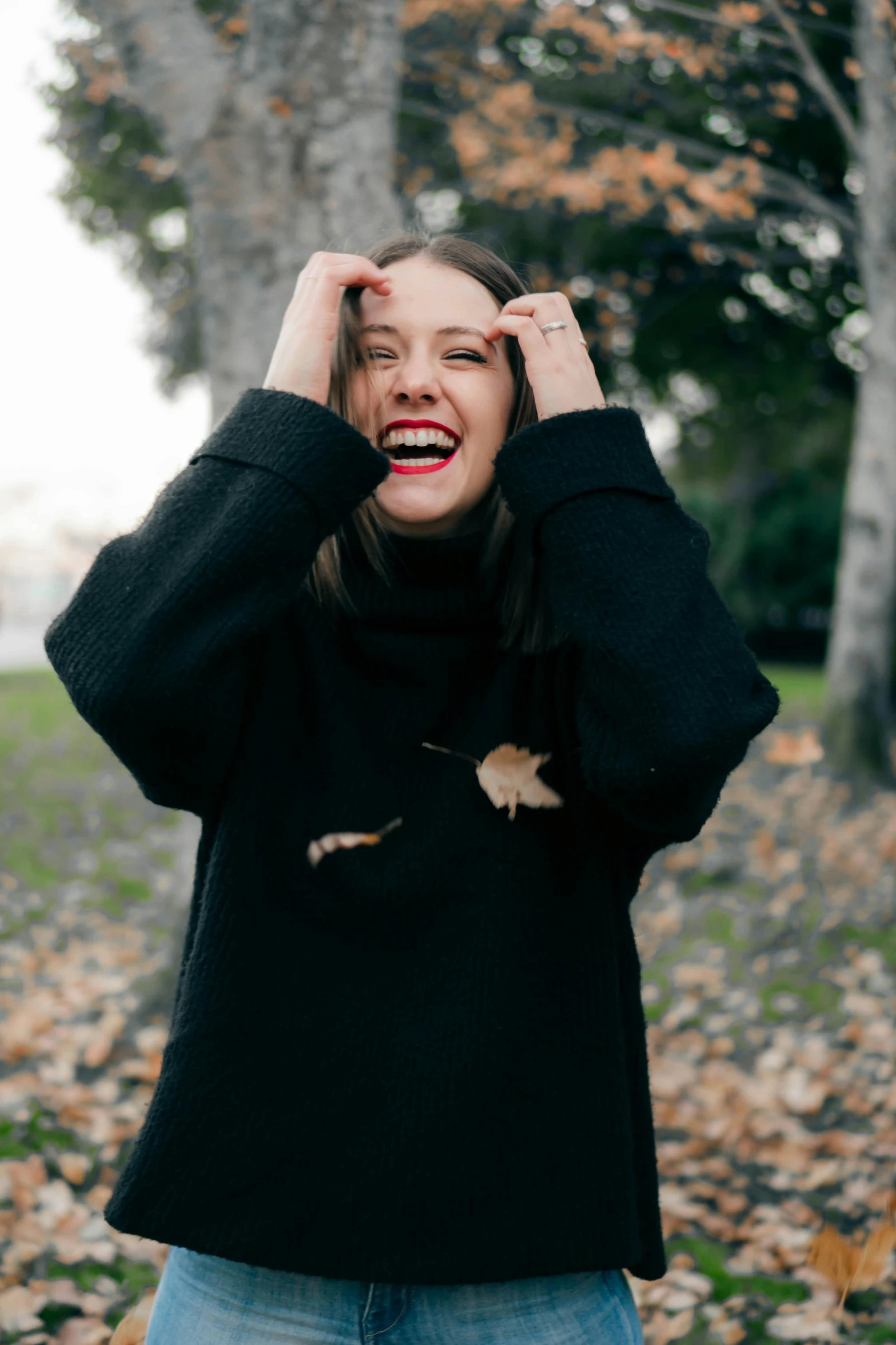 a woman standing in a park with her hands on her head, pexels contest winner, happening, wearing a black sweater, laughing hysterically, pokimane, black turtle neck shirt