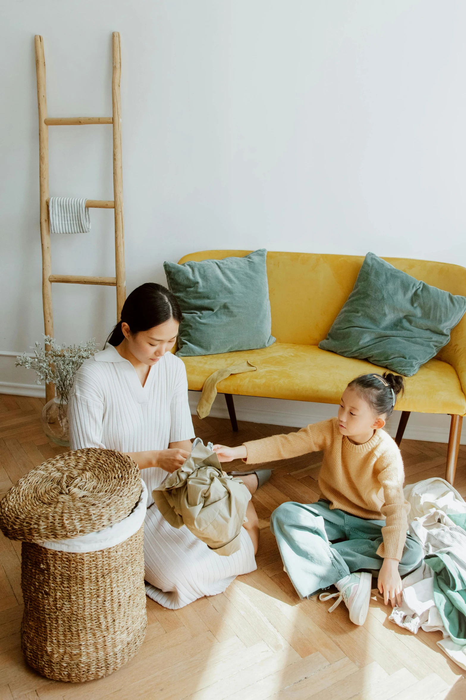 a woman sitting on the floor next to a child, pexels contest winner, minimalism, presenting wares, at the sitting couch, promotional image, asian descent