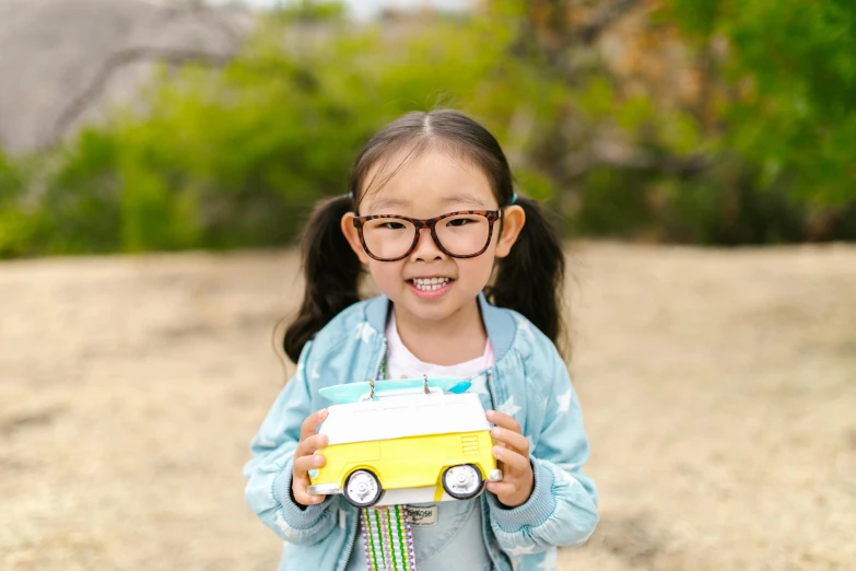 a little girl wearing glasses holding a toy car, pexels contest winner, shin hanga, ice! cream! truck!, bulli, avatar image, square rimmed glasses