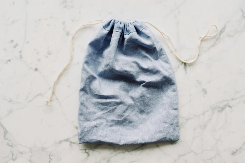 a blue bag sitting on top of a marble counter, by Nina Hamnett, unsplash, wearing a linen shirt, recipe, ffffound, listing image