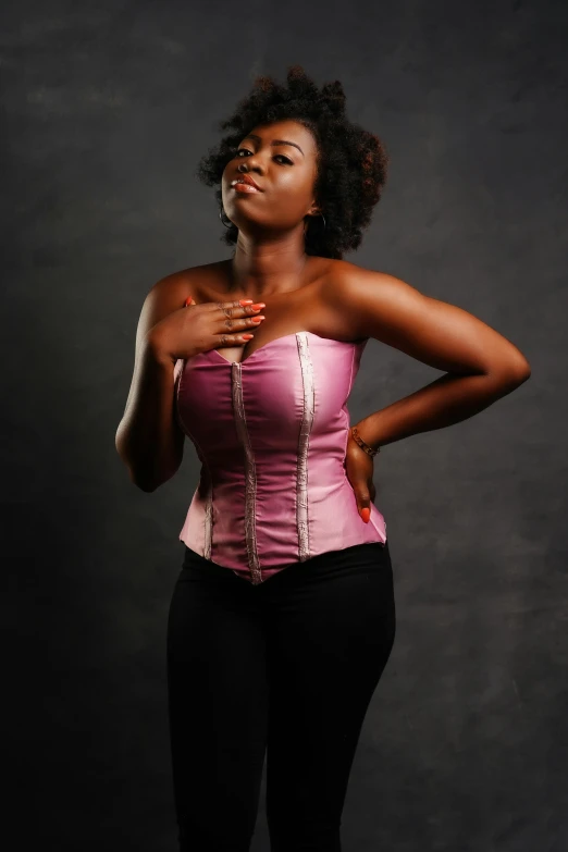 a woman in a pink corset posing for a picture, by Ella Guru, dark skin tone, plain background, trending photo, aged 2 5