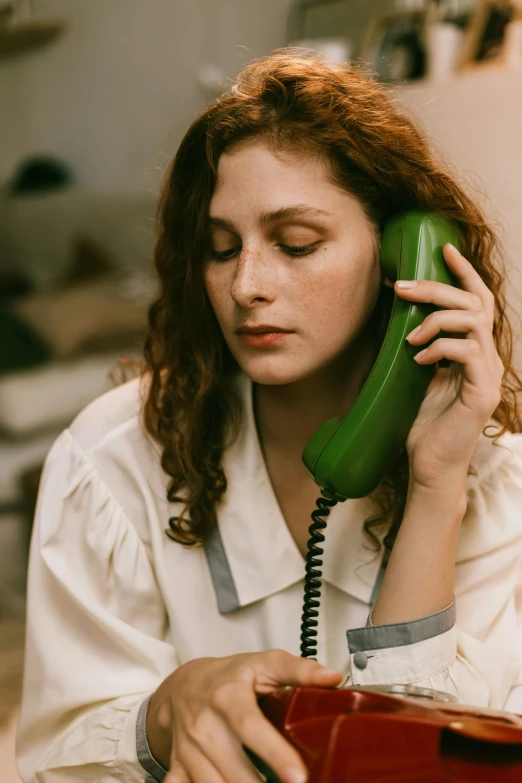 a woman sitting at a table talking on a phone, a photo, inspired by Elsa Bleda, trending on pexels, renaissance, green and brown clothes, a telephone receiver in hand, worried, photo of young woman