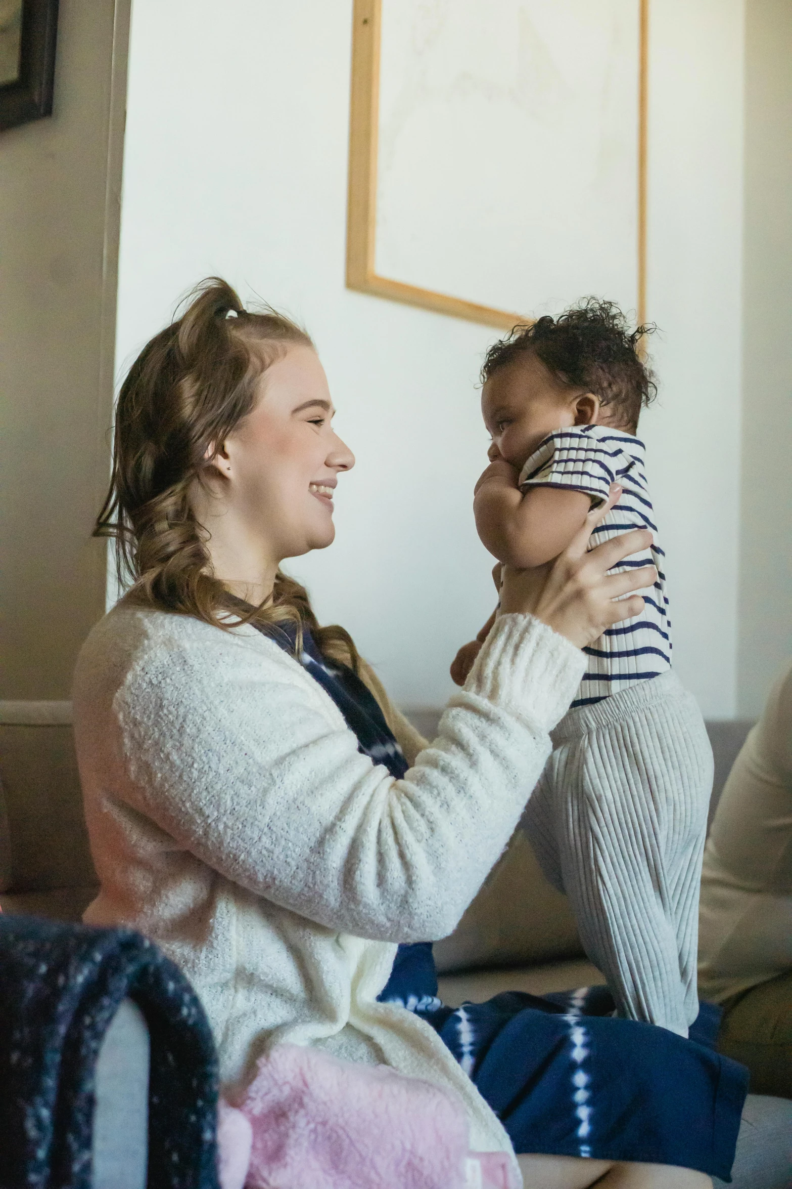 a woman sitting on a couch holding a baby, pexels contest winner, happening, mixed race, holding each other, a blond, supportive