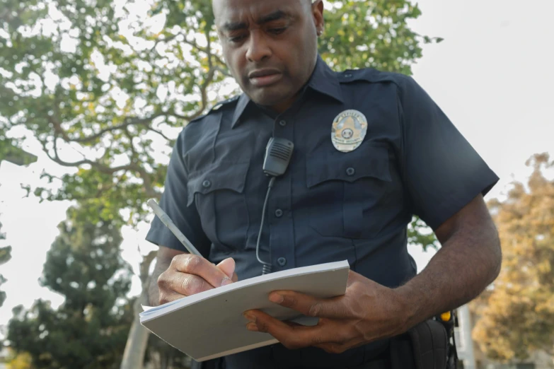 a man in a police uniform writing on a clipboard, diverse, thumbnail, digital image, contain