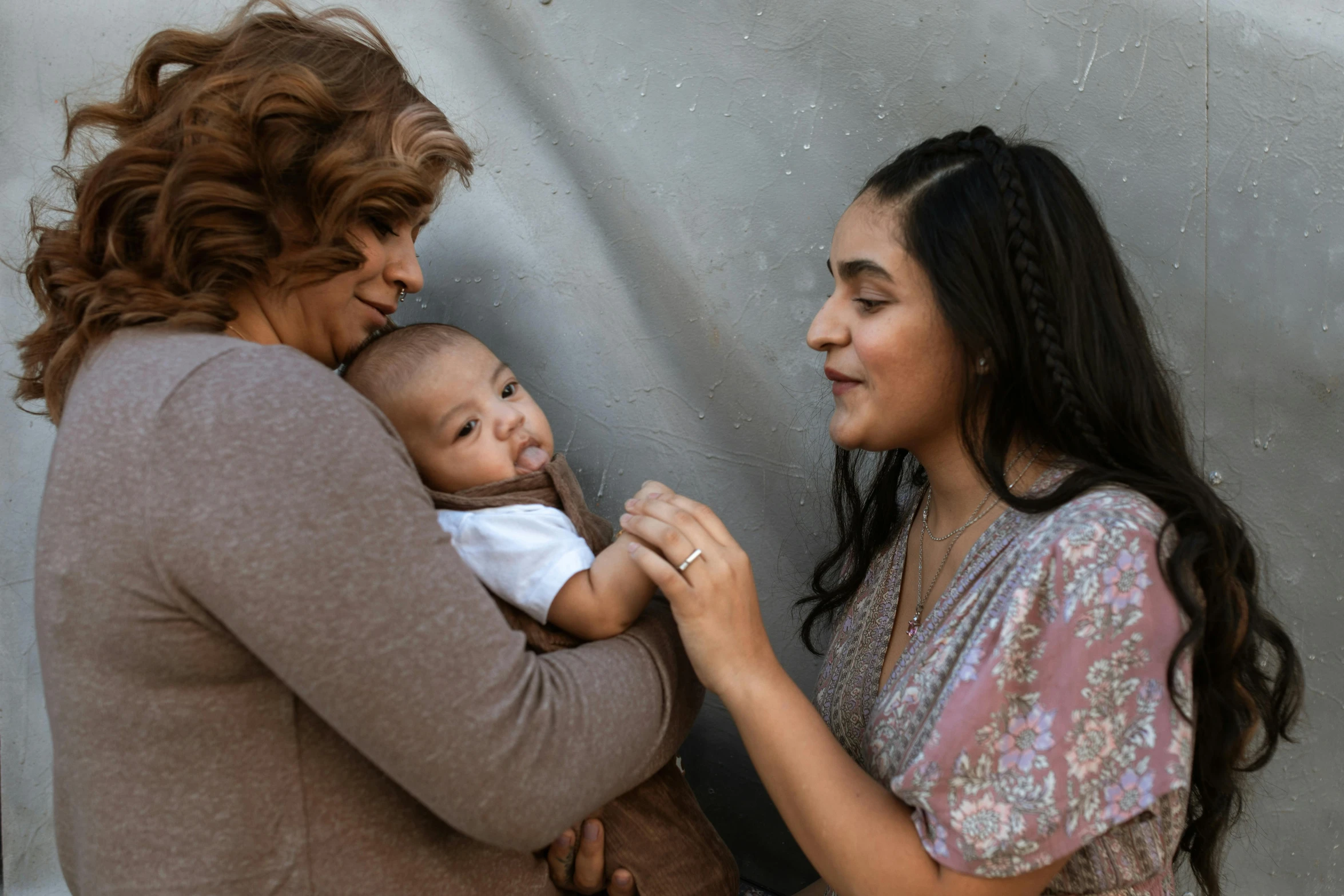 a woman standing next to a woman holding a baby, pexels contest winner, an olive skinned, lesbian, profile image, middle eastern skin