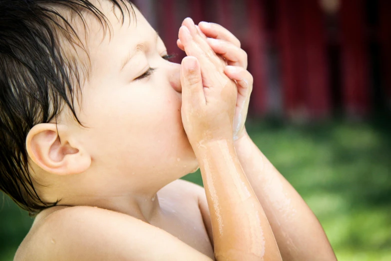 a young child drinking water from a sprinkler, an album cover, by Ellen Gallagher, shutterstock, sunbathed skin, 15081959 21121991 01012000 4k, hand on his cheek, skincare