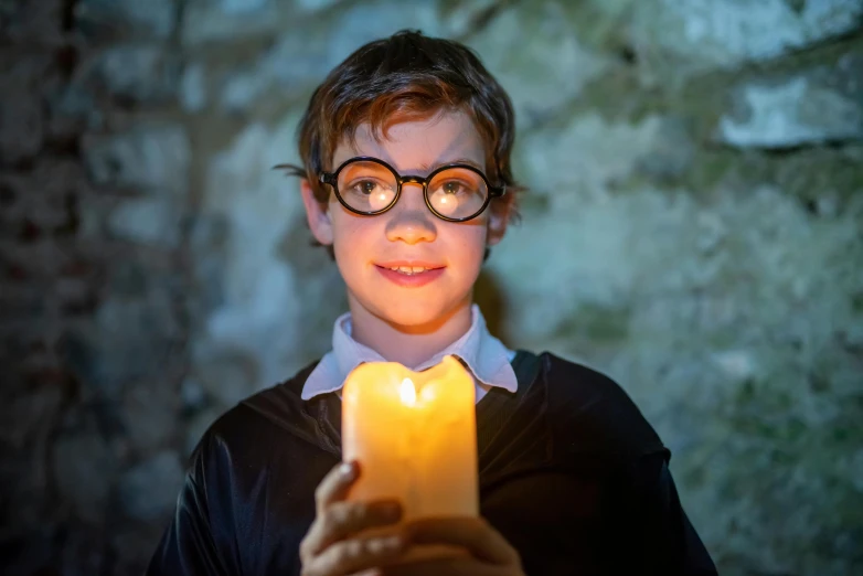 a boy with glasses holding a lit candle, immersive, harry, a friendly wisp, professionally taken