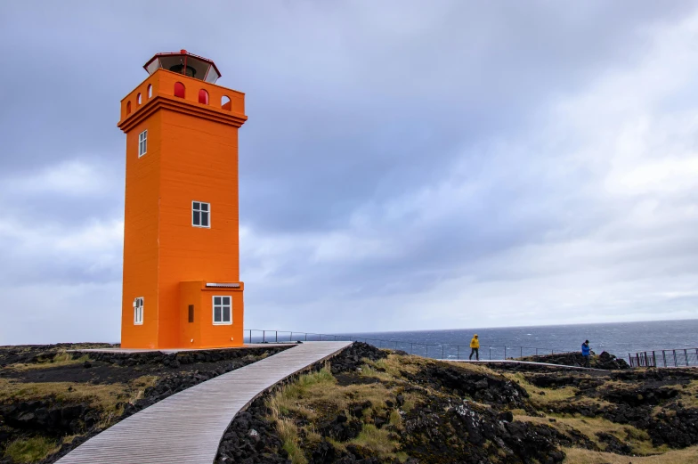 a lighthouse sitting on top of a hill next to the ocean, by Hallsteinn Sigurðsson, yellow orange, square, tourist photo, orange neon