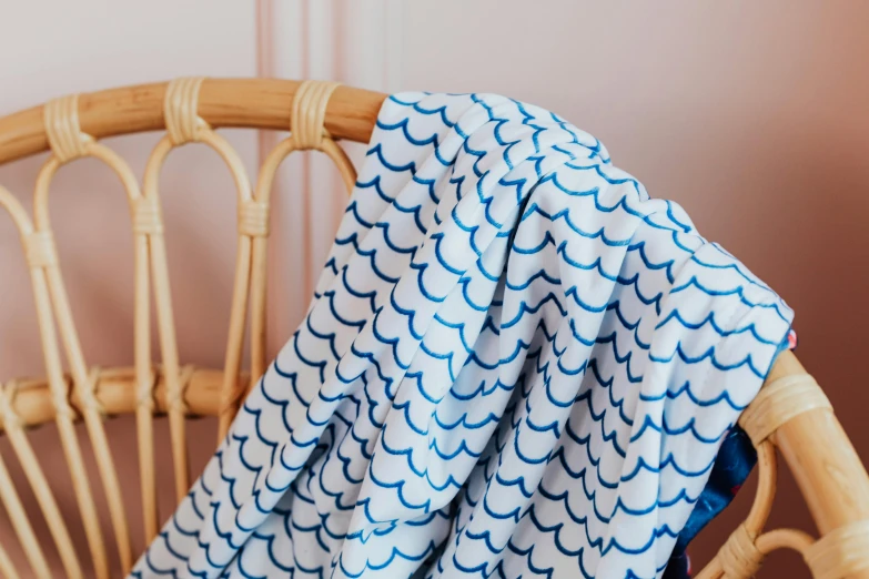 a blue and white blanket sitting on top of a chair, by Helen Stevenson, unsplash, fish scales, shower cap, screen printed, épaule devant pose