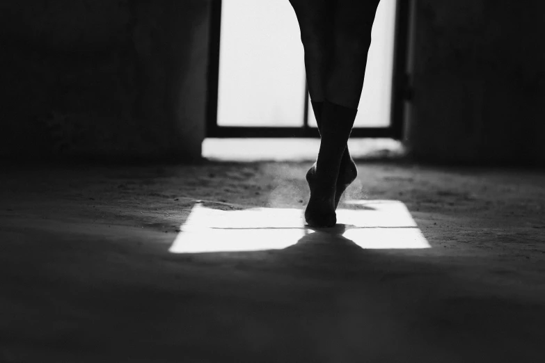 a black and white photo of a woman's legs, by Maciej Kuciara, unsplash, arabesque, ears shine through the light, hoofs, about to enter doorframe, choreographed
