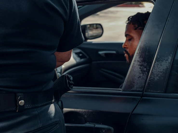 a man sitting in the driver's seat of a car, pexels contest winner, happening, arrested, wearing a police uniform, looking in the window, holding court