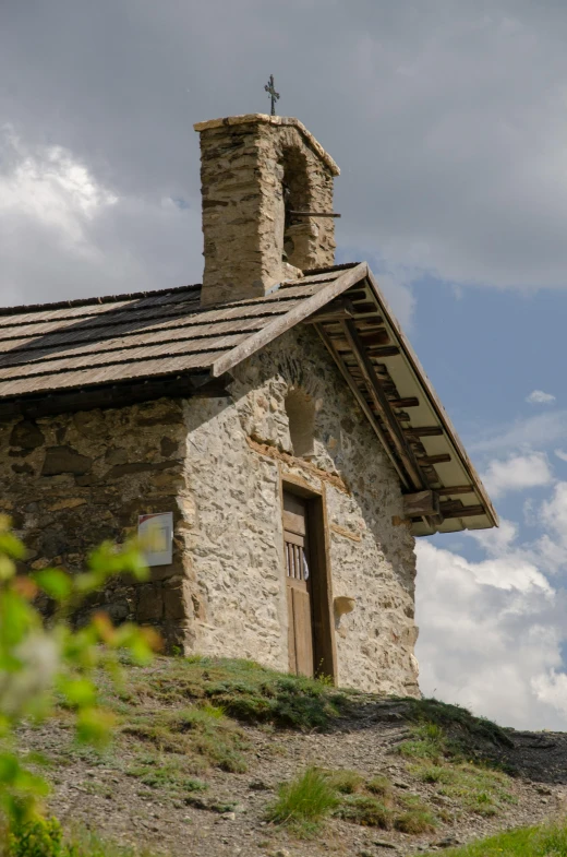 a small stone building sitting on top of a hill, unsplash, romanesque, chalet, detail shot, color image, no cropping