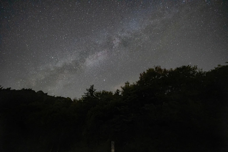 a boat sitting on top of a body of water under a night sky, in the forest at night