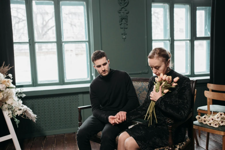 a man and a woman sitting next to each other, by Emma Andijewska, pexels contest winner, romanticism, wilted flowers, casual black clothing, sitting on an armchair, hammershøi