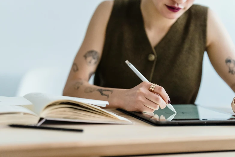 a woman sitting at a table writing on a piece of paper, a drawing, trending on pexels, academic art, 9 9 designs, androgynous person, draw with wacom tablet, rounded corners