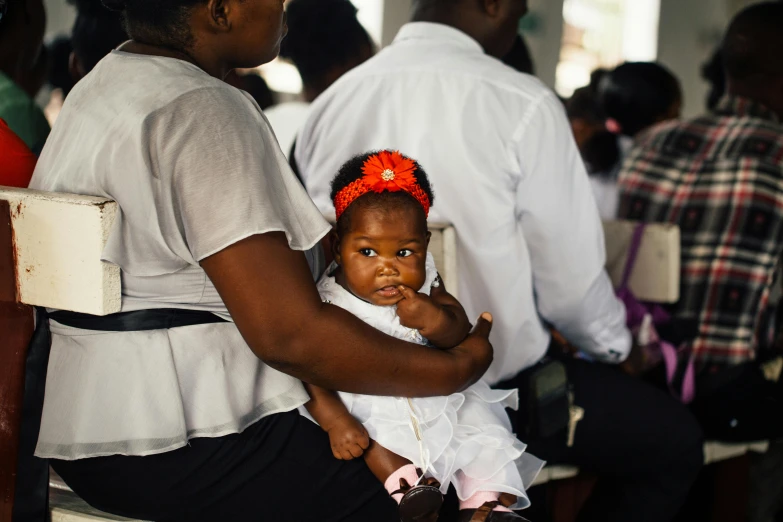 a woman holding a baby sitting on top of a chair, by Daniel Lieske, pexels contest winner, jamaica, baptism, square, schools