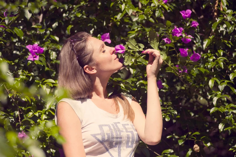 a woman standing in front of a bush of purple flowers, a photo, drinking, paradise garden massage, profile image, ekaterina