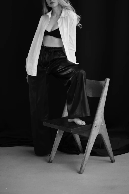 a woman sitting on top of a wooden chair, inspired by August Sander, unsplash, leather pants, showstudio, 👰 🏇 ❌ 🍃, summer night