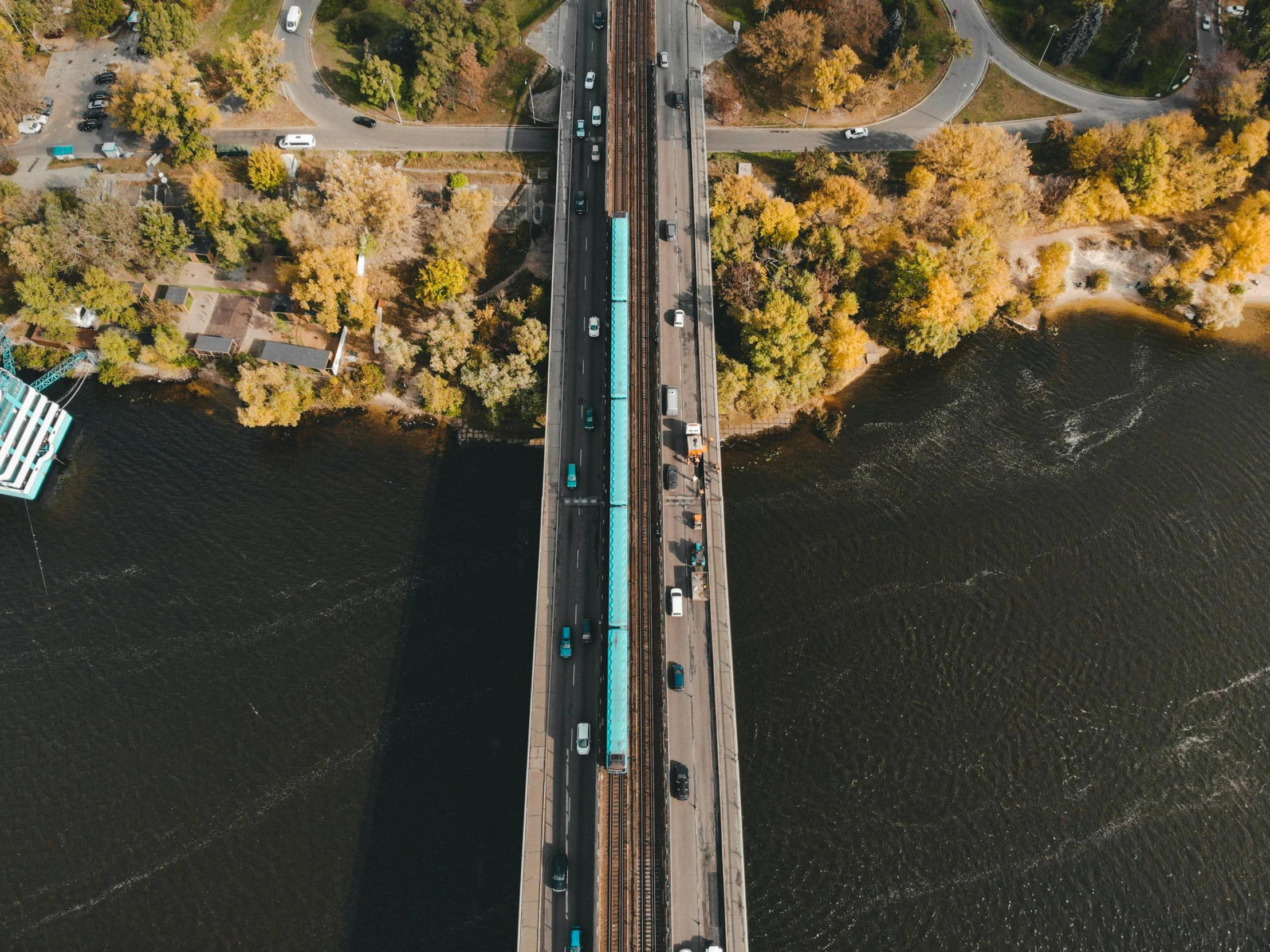 a train traveling across a bridge over a river, pexels contest winner, satellite imagery, minneapolis, brown and cyan color scheme, cars on the road