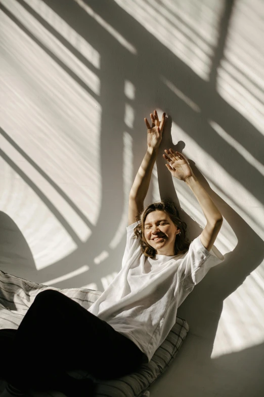 a woman sitting on top of a bed next to a window, pexels contest winner, light and space, triumphant pose, sun and shadow, white backdrop, happy friend