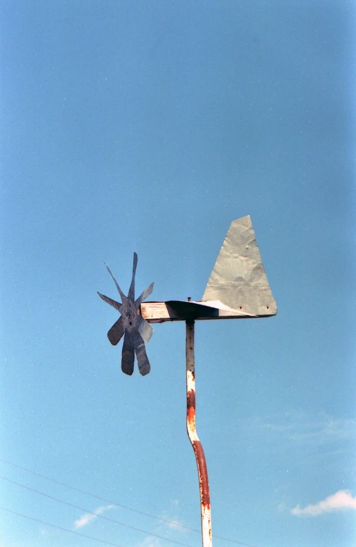 a windmill on a pole with a blue sky in the background, an abstract sculpture, by Attila Meszlenyi, kinetic art, 1971, rabbit ears, ((rust)), album