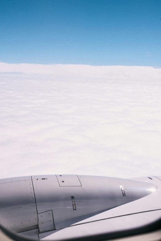 a view of the wing of an airplane through a window, by Peter Churcher, hurufiyya, above low layered clouds, f/2.8, low horizon, viewed from bird's-eye