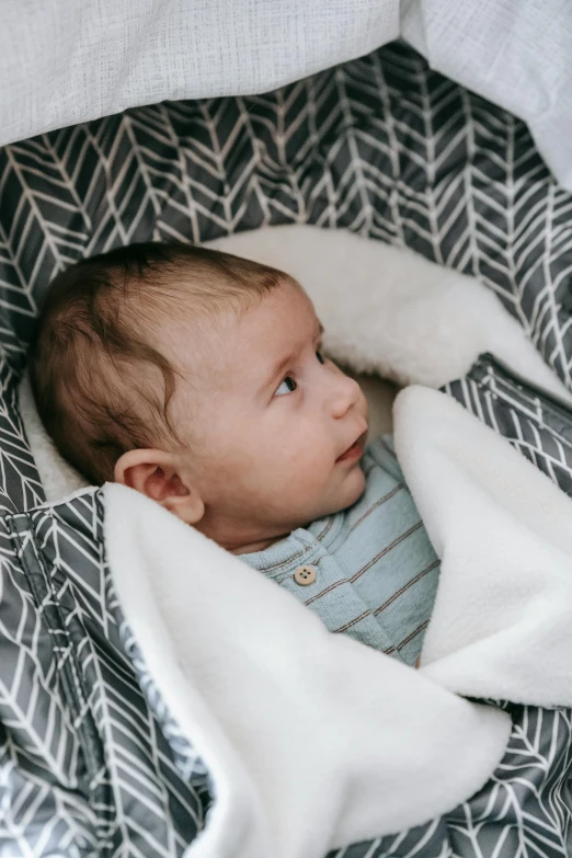 a close up of a baby wrapped in a blanket, unsplash, happening, vehicle, geometric, grey, patterned